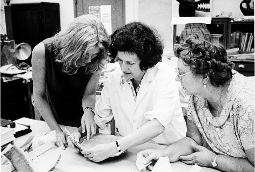 National Museum of Natural History's Anthropology Conservation Laboratory volunteer Edith Deitz (right) looking at an artifact in the laboratory with staff members.
